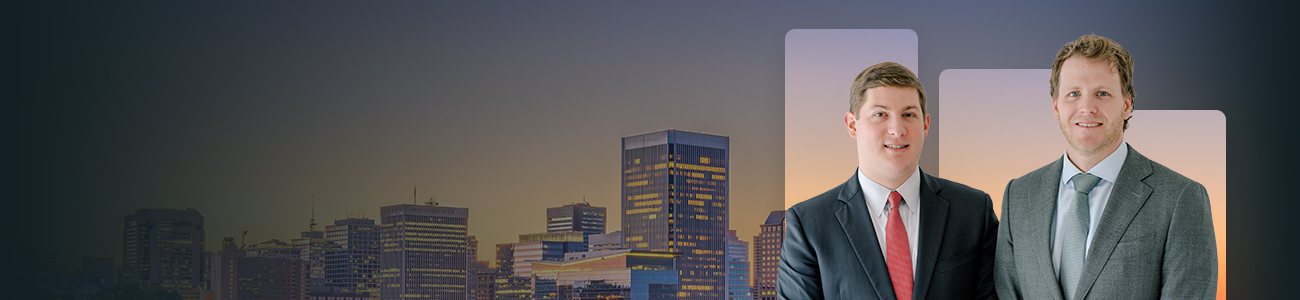 Attorneys Bay Lawrence and Cameron McCormick standing in front of a city skyline.